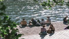 several people sitting on the ground near water