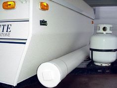 a white rv parked in a garage next to a propane tank