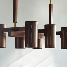 a chandelier made out of wood and metal tubes hanging from it's sides