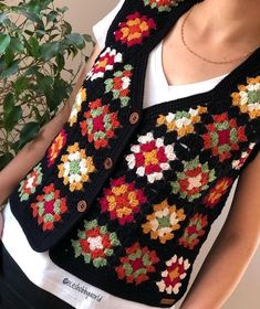 a woman wearing a black crocheted vest with multicolored flowers on it