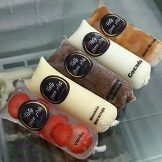 four different flavors of ice cream and strawberries on display in a store window case