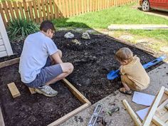 a man kneeling down next to a little boy in the dirt with tools on it