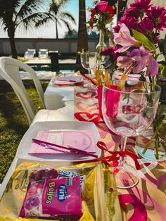 the table is set with pink flowers and other items for guests to eat on it