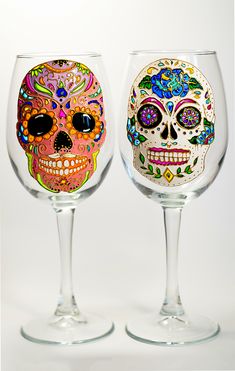 two wine glasses decorated with colorful sugar skulls