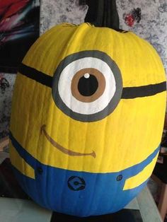 a yellow and blue pumpkin with an eyeball on it's face, sitting on a table