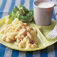 a plate with macaroni and cheese next to a cup of milk