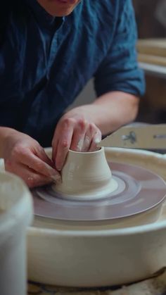 a woman is making a vase out of clay on a potter's wheel with her hands