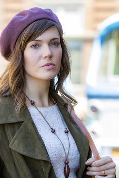 a woman wearing a purple hat and green jacket