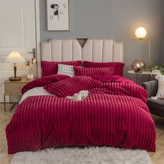 a bed with red comforter and pillows in a room