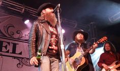 two men with long hair and beards are playing guitars on stage at a concert