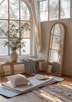 a large mirror sitting on top of a wooden floor next to a table with pillows