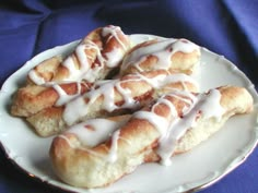 a white plate topped with pastry covered in icing on top of a blue cloth