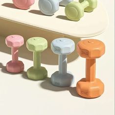 an assortment of colored dumbs are lined up on a white surface, with one in the foreground