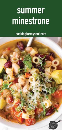 a white bowl filled with pasta and vegetables on top of a table next to a spoon