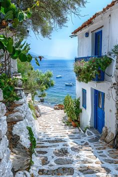 an alley leading to the beach with blue shutters and flowers growing on the windows