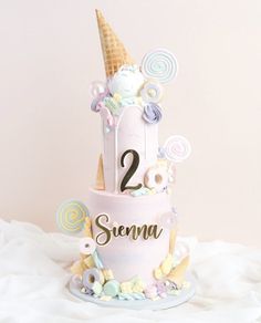 a two tiered cake with ice cream cones on top and candy in the middle