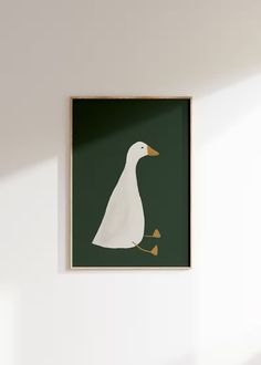 a white duck in a green frame hanging on the wall next to a plant and potted plant