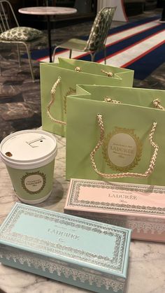 several different colored paper bags sitting on top of a table next to a cup of coffee