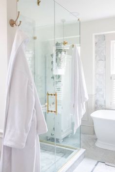 a bathroom with a glass shower door and white towels hanging on the wall next to it