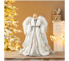 an angel figurine sitting on top of a table next to a christmas tree