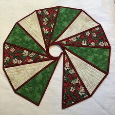 a green and white quilted table topper with red trimmings on it