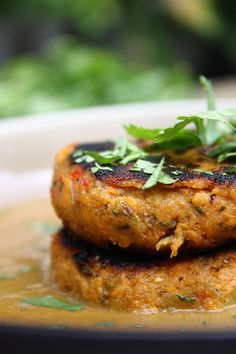 two patties are stacked on top of each other in broth and garnished with parsley