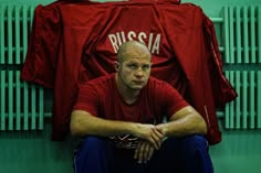 a man sitting on the ground in front of some red shirts