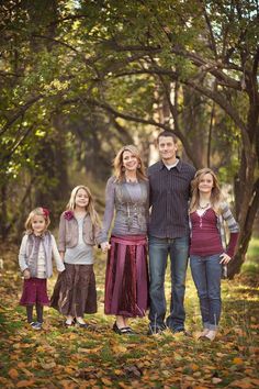 the family is posing for a photo in front of some trees with leaves on them