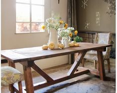 a wooden table with vases and flowers on it in front of a large window