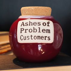 a red jar with a cork top that says ashes of problem customers