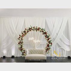 a chair sitting in front of a white backdrop with roses and greenery on it