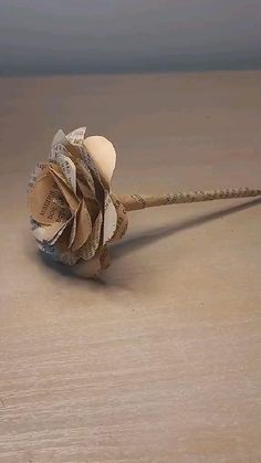 a flower that is sitting on top of a wooden table next to some string and paper