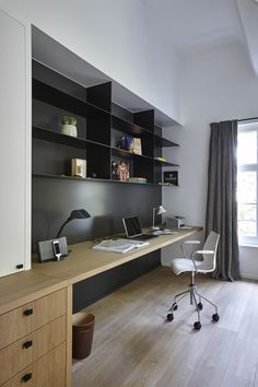 a desk with a laptop computer on top of it next to a book shelf filled with books