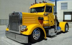 a yellow semi truck parked in front of a building