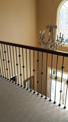 a chandelier hanging from the side of a stair case next to a window