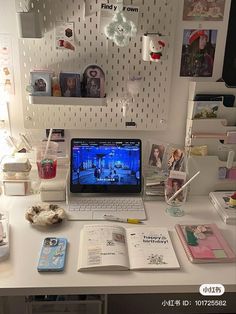 an open laptop computer sitting on top of a white desk covered in pictures and photos