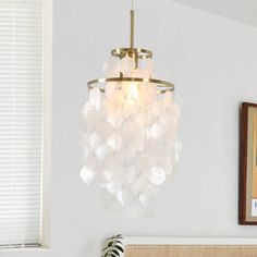 a chandelier hanging from the ceiling over a bed in a room with white walls