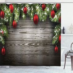 a christmas themed shower curtain with red ornaments and pine branches on the wooden wall behind it