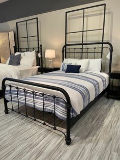 two beds in a room with white and blue bedding on the floor, one has a black metal frame