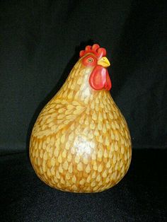 a wooden chicken figurine sitting on top of a black table next to a wall