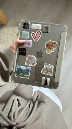 a person holding up an ipad with stickers on the back of it's cover