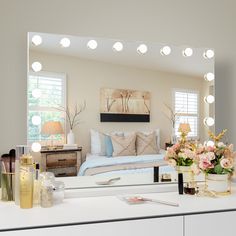 a bedroom with vanity lights and flowers on the dresser next to it's mirror