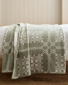 a green and white blanket on top of a bed