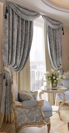 a living room filled with furniture and a window covered in draping next to a table