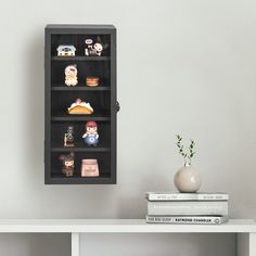 a book shelf with several small figurines on top of it next to a vase and books