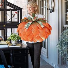 a woman is carrying a large pumpkin decoration