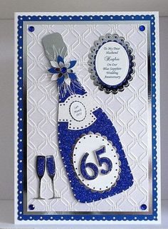 a blue and white birthday card with a wine bottle on the front, two glasses in the back