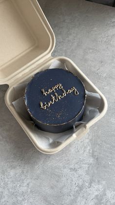 a blue cake in a white box on the floor next to a black and gold sign