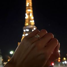 a person holding their hand in front of the eiffel tower