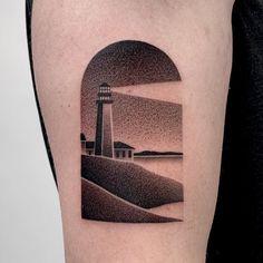 a man's arm with a lighthouse tattoo on the left side of his body